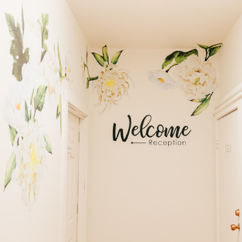 Entrance hallway of Seneca Falls Acupuncture, with golden floral wall design and large sign that says, "Welcome, Reception."